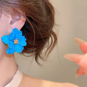 Detailopname van een blauwe bloemknop oorbel met een gouden getextureerd midden