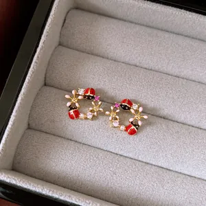 Detailaufnahme von Vintage-Marienkäfer-Ohrringen mit rosa Blumen und Kristalldetails.