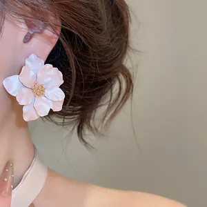 Gedetailleerd zicht op een elegante witte bloem oorknop met gouden meeldraden