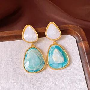 Detailansicht von geometrischen Vintage-Ohrhängern mit blau-weißem Marmor-Resin-Design