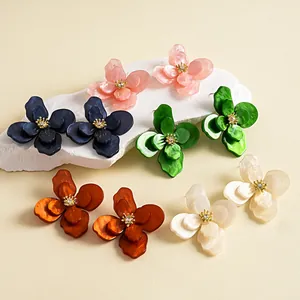 Dettaglio di orecchini vintage in acrilico marmorizzato a forma di fiore con cristalli.