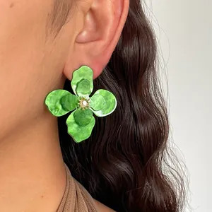 Dettaglio di orecchini a fiore in acrilico verde vintage con centro in strass scintillanti