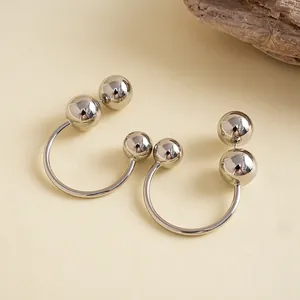 Détail de boucles d'oreilles géométriques argentées en forme de C avec boules