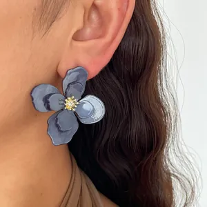 Dettaglio ravvicinato di orecchino a fiore vintage in acrilico grigio con strass sull'orecchio.