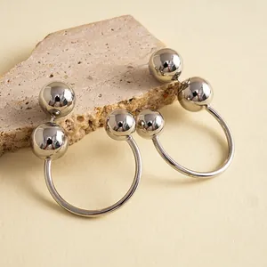 Vue détaillée de boucles d'oreilles minimalistes en forme de C avec des billes chromées.