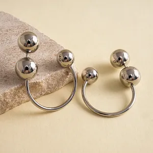 Vue détaillée de boucles d'oreilles C en métal poli avec design sphérique
