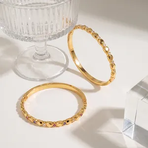 Macro view of stylish gold-tone stainless steel bangles featuring colorful zircon stones