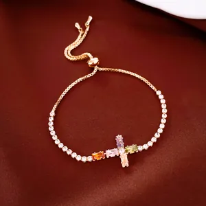 Bracelet croix ajustable plaqué or orné de pierres de zircone cubique multicolores.