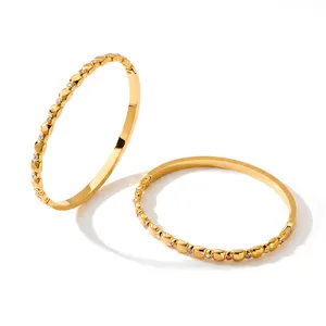 Detailed macro view of geometric gold bangles featuring colorful inlaid cubic zirconia stones