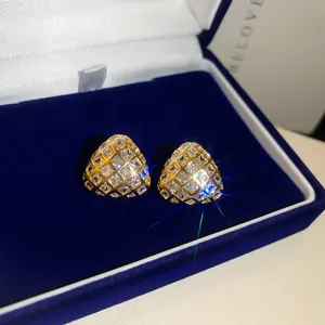 Detail van 18k vergulde driehoekige oorknopjes met glinsterende zirkoniasteentjes.