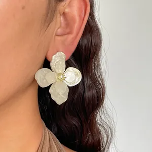 Primo piano di un orecchino a fiore in acrilico bianco con centro in strass