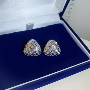 Detailopname van fonkelende driehoekige zirkonia oorknopjes met ruitpatroon in blauwe doos