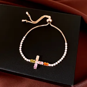 Vue détaillée de la croix en zircon coloré sur un élégant bracelet ajustable plaqué or.