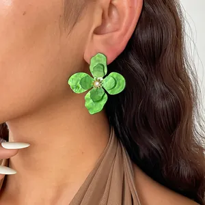 Dettaglio di orecchini a fiore in acrilico verde retrò con piccoli strass al centro