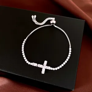 Détail d'un bracelet bolo argenté orné d'un pendentif en croix de zircon étincelant.
