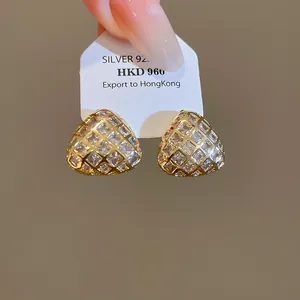 Gedetailleerde macro-opname van driehoekige 18k vergulde oorbellen met fonkelende zirkonia