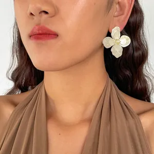 Dettaglio di una modella che indossa orecchini a fiore in acrilico con strass dorati