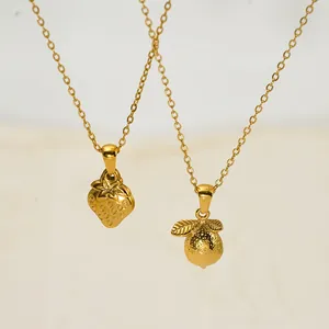 Détail d'un collier en acier inoxydable doré avec pendentifs fraise et citron élégants