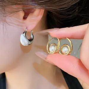 Detailed close-up of vintage gold and silver pearl drop hoop earrings worn by a model