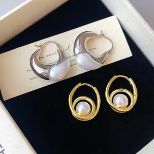 Detailed view of French vintage gold swirl pearl hoop and silver droplet earrings