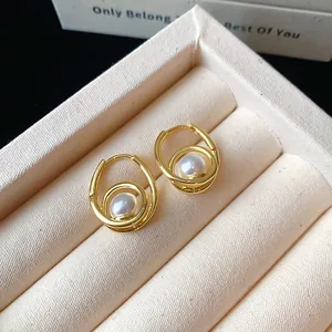 Close-up detail of French vintage style gold hoop earrings with elegant white pearl drops