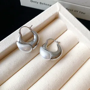 Detailed macro shot of vintage-style silver hoop earrings with white pearl teardrop inlay