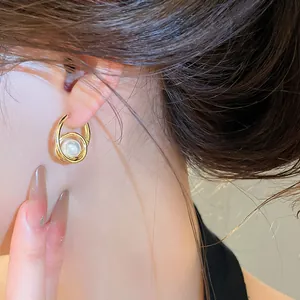 Close-up of a model wearing elegant French vintage gold hoop earrings with pearls.