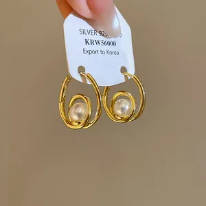 Detail view of elegant French style gold teardrop hoop earrings with lustrous white pearls.