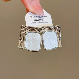 Dettaglio di orecchini quadrati in argento pieghettato con inserto in madreperla