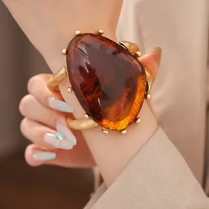 Detailansicht eines klobigen Statement-Armbands aus bernsteinfarbenem Harz mit Goldbeschlag