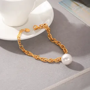 Détail d'un bracelet chaîne en or vintage avec un grand pendentif en perle blanche.