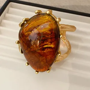 Nahaufnahme eines großen Armreifs aus bernsteinfarbenem Harz mit goldener Struktur