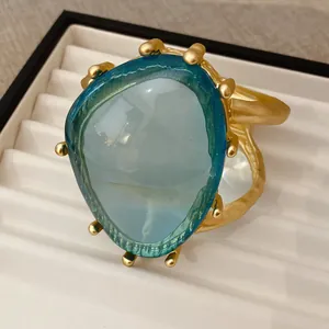 Detailansicht eines übergroßen blauen Harzarmreifens mit goldfarbenem Hohlmetalldesign