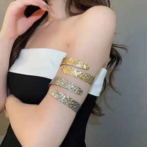 Detailweergave van de onregelmatige gehamerde metalen armmanchet in goud- en zilverafwerking