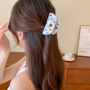 Close-up of a trendy blue and brown polka dot hair claw clip in a half-up hair style