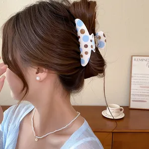 Detail showing the blue and brown polka dot hair claw clip used in a low bun hairstyle