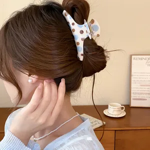 Detailed visual of a stylish white hair claw clip with blue and brown polka dot patterns
