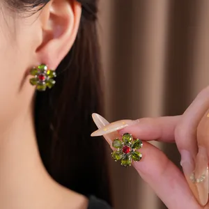 Detailaufnahme des Vintage-Blumenohrrings mit grünem Zirkon und rotem Kern