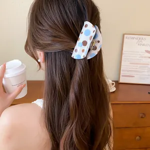 Close-up showing a polka dot hair claw clip styling wavy brown hair in a cafe