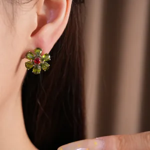 Nahaufnahme eines Vintage-Blumenohrsteckers mit grünen und roten Zirkoniasteinen