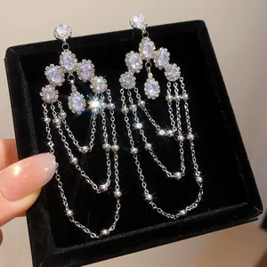 Macro detail of elegant silver-tone dangle earrings with oval zircons and long tassels
