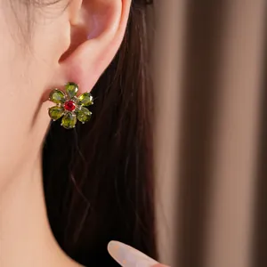 Detailansicht eines grünen und roten Zirkonia-Blumenohrrings im Vintage-Stil am Ohr