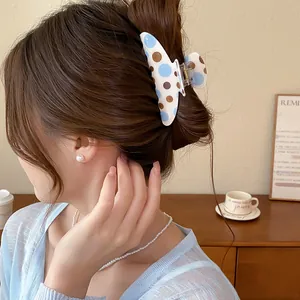 Close-up of a retro blue and brown polka dot hair claw clip elegantly worn on a bun.