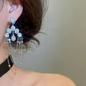 Close-up of luxury sparkling long tassel earrings with oval zircons shown on model
