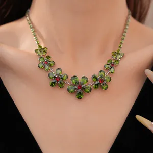 Detailansicht einer Vintage-Blumenhalskette mit grünen und roten Zirkonien am Modellhals