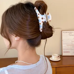 Detailed shot of a vintage blue and brown polka dot hair claw clip in a bun hairstyle