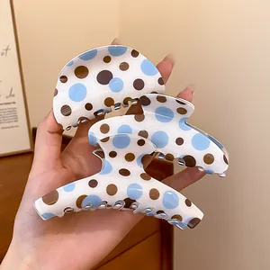 Close-up detail of three Korean style hair claw clips featuring blue and brown polka dots