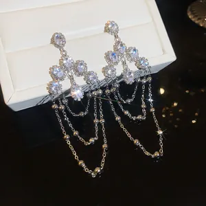 Macro view of sparkling oval zirconia tassel earrings featuring delicate multi-layer chains