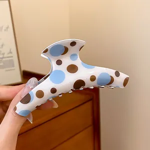 Macro view of a vintage style hair claw clip featuring blue and brown polka dots