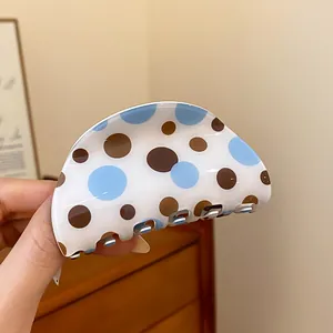 Detailed macro view of a vintage style hair claw clip featuring blue and brown polka dots
